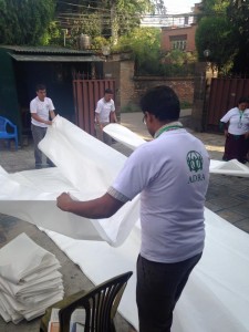Funcionários da ADRA Internacional e da ADRA Nepal preparam lonas que serão distribuídas para abrigar vítimas do terremoto. Foto: ADRA Nepal