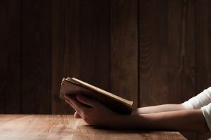 woman reading the bible in the darkness over wooden table